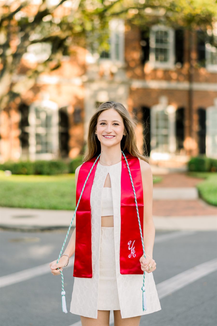 Annabelle Reed on the University of Alabama campus, wearing a crimson graduation stole and honor cords.